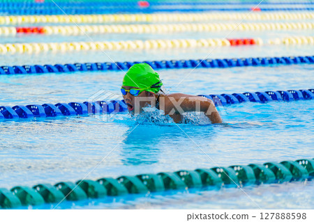Swimmer child swims butterfly swimming style in a race swimming pool. Water sports and competition, learning to swim classes for children. 127888598