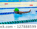 Swimmer child swims butterfly swimming style in a race swimming pool. Water sports and competition, learning to swim classes for children. 127888599