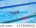 Swimmer child swims backstroke swimming style in a race swimming pool. Water sports and competition, learning to swim classes for children. 127888602