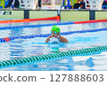 Swimmer child swims breaststroke swimming style in a race swimming pool. Water sports and competition, learning to swim classes for children. 127888603