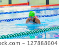 Swimmer child swims breaststroke swimming style in a race swimming pool. Water sports and competition, learning to swim classes for children. 127888604