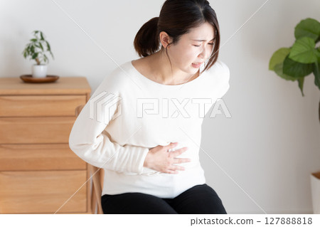 Unwell woman holding her stomach and back Unwell woman holding her stomach and back 127888818