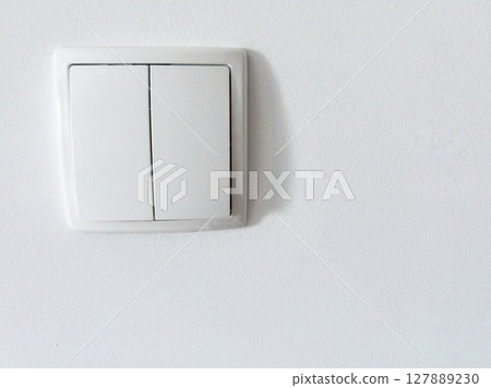 White plastic light switch on clean white wall interior detail minimal concept. Ideal for illustrating energy saving 127889230