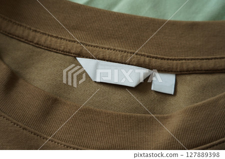 Close up of blank white clothing care label on shirt fabric background. 127889398