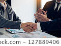 Businessmen shaking hands while completing work. 127889406