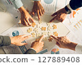 The concept of teamwork and partnership. Businessman's hands putting together puzzle pieces in the office and join together in a jigsaw puzzle team. Charity. Volunteers. Business unity as a team. 127889408