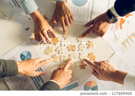 The concept of teamwork and partnership. Businessman's hands putting together puzzle pieces in the office and join together in a jigsaw puzzle team. Charity. Volunteers. Business unity as a team. 127889408