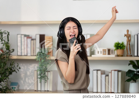 Singing and Joy. Young woman enjoying music with headphones at home. Singing and Joy. Young woman enjoying music with headphones at home. 127889840