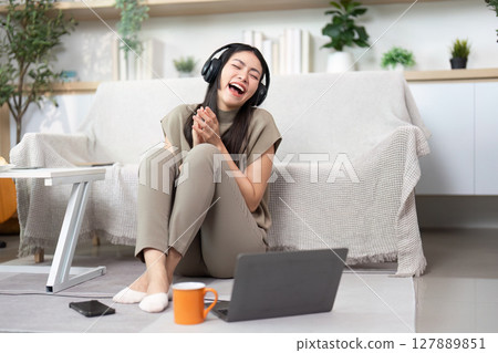Remote Work and Relaxation. Young woman enjoying music while working from home. 127889851