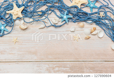 Fishing net, seashells, and starfishes creating a seaside border on wooden planks Fishing net, seashells, and starfishes creating a seaside border on wooden planks 127890604