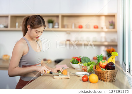 Wellness and Cooking Skills. Young woman chopping vegetables in a bright kitchen. 127891375