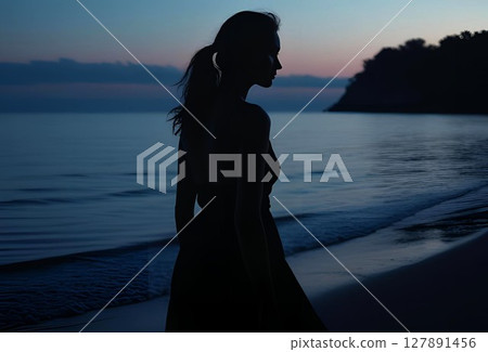 Silhouette of a young woman standing on the beach at sunset 127891456