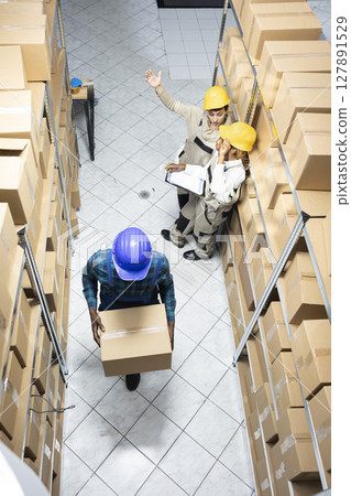Diverse employees group preparing parcels and managing stock in an organized warehouse depot facility. Logistics center staff supports retail distribution and operational effectiveness. Diverse employees group preparing parcels and managing stock in an organized warehouse depot facility. Logistics center staff supports retail distribution and operational effectiveness. 127891529