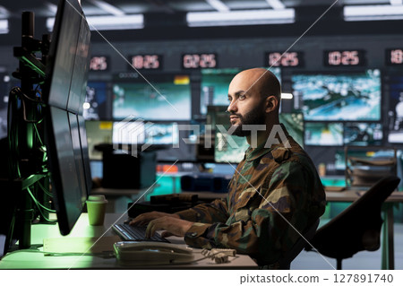 Counterterrorism division officer in command center using target acquisition tech to detect enemy location. Middle Eastern defense security agent using satellite equipment to track threats Counterterrorism division officer in command center using target acquisition tech to detect enemy location. Middle Eastern defense security agent using satellite equipment to track threats 127891740