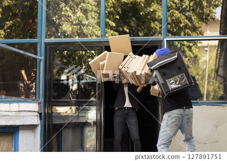 Delivery man lets a tall stack of pizza boxes crash to the floor, client catching him drop the food. Poorly trained courier stumbling and destroying the order delivery, bad service. Delivery man lets a tall stack of pizza boxes crash to the floor, client catching him drop the food. Poorly trained courier stumbling and destroying the order delivery, bad service. 127891751