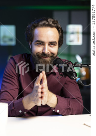 Portrait of happy media star talking in professional microphone in studio at night, filming internet video production. Smiling content creator uses quality mic to record vlog and speak to viewers Portrait of happy media star talking in professional microphone in studio at night, filming internet video production. Smiling content creator uses quality mic to record vlog and speak to viewers 127891774
