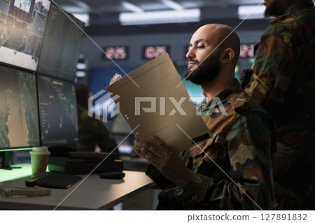 Military officer reviews battlefield data documents after conducting surveillance, supporting field troops. Counterintelligence operative reading mission case file, getting debriefed on enemies Military officer reviews battlefield data documents after conducting surveillance, supporting field troops. Counterintelligence operative reading mission case file, getting debriefed on enemies 127891832