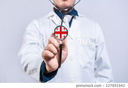Doctor hands holding stethoscope with Georgia flag. Georgia health and care concept 127891842