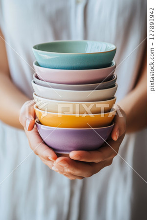 Hands Holding a Stack of Colorful Ceramic Bowls Hands Holding a Stack of Colorful Ceramic Bowls 127891942
