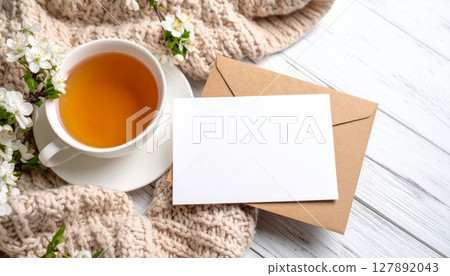 Warm brown tea in a ceramic mug on a wooden table with a blank card, perfect for a cozy morning breakfast or business break 127892043