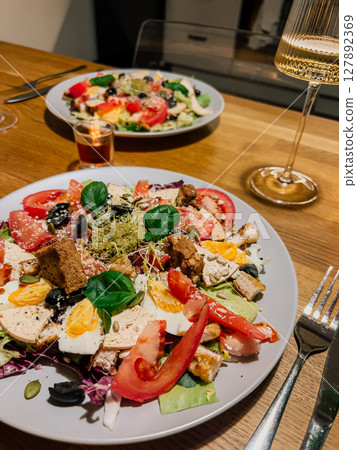 Romantic dinner with salad and wine, romantic setting under candlelight, romantic food moment with fresh ingredients and elegance. Dinner date with healthy salad and wine. Date night, colorful plates Romantic dinner with salad and wine, romantic setting under candlelight, romantic food moment with fresh ingredients and elegance. Dinner date with healthy salad and wine. Date night, colorful plates 127892369
