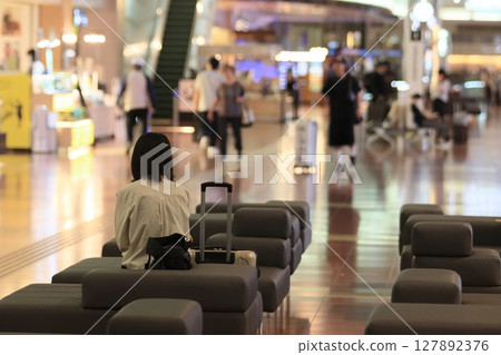 Back view of a woman waiting in the departure lobby at the airport 127892376