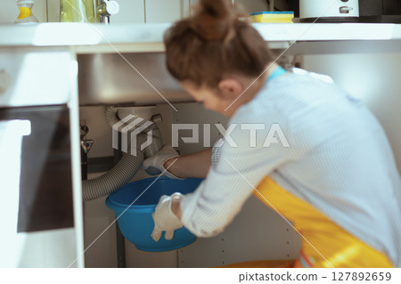 Woman Fixing Kitchen Sink Plumbing 127892659