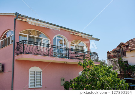 Pink house with balcony and arched windows 127893194