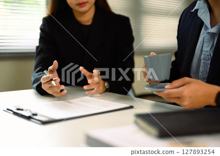 Close up of business professionals reviewing a contract together at a modern office desk 127893254