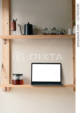 Kitchen shelf with laptop, glass coffee pot and stylish coffee accessories Kitchen shelf with laptop, glass coffee pot and stylish coffee accessories 127893286