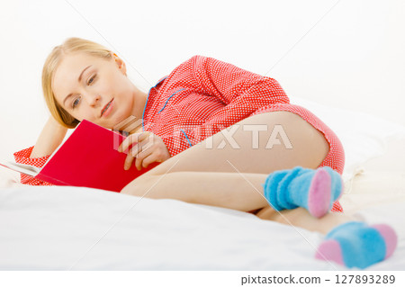 Woman relaxing in bed reading book Woman relaxing in bed reading book 127893289
