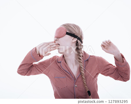 Sleepy woman wearing pink eye band 127893295