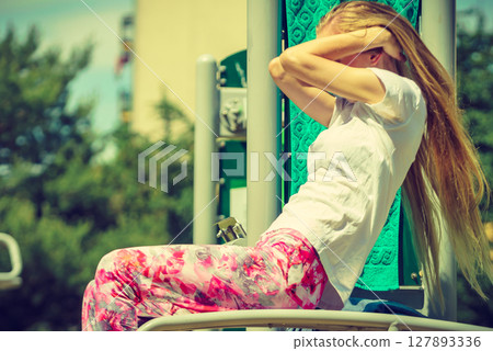 Girl doing situps in outdoor gym 127893336