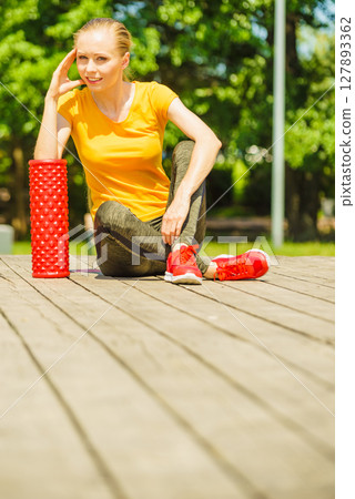 Girl doing exercises outdoor, using roller 127893362