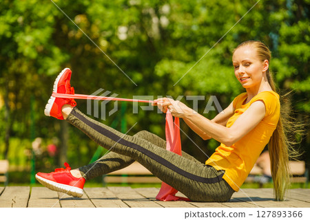 Girl doing exercise outdoor, using resistance fit band. Girl doing exercise outdoor, using resistance fit band. 127893366