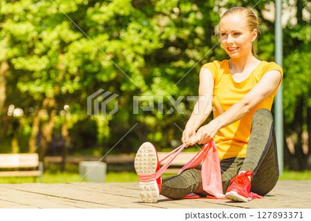 Girl doing exercise outdoor, using resistance fit band. Girl doing exercise outdoor, using resistance fit band. 127893371