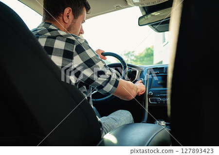 Man pressing car engine start button inside vehicle Man pressing car engine start button inside vehicle 127893423