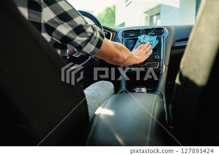 Man cleaning car dashboard from inside of car Man cleaning car dashboard from inside of car 127893424