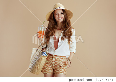 smiling stylish woman in blouse and shorts on beige 127893474
