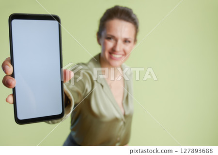 Smiling woman presenting smartphone screen 127893688