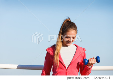 Woman doing sports outdoors with dumbbells 127893821