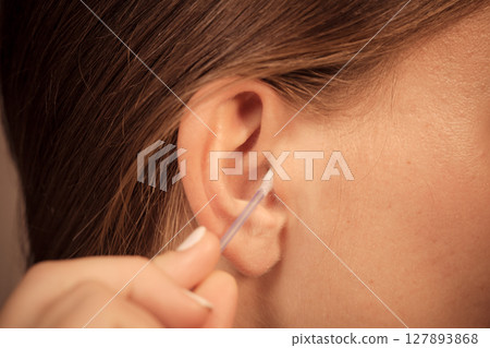 Woman cleaning ear with cotton swabs closeup Woman cleaning ear with cotton swabs closeup 127893868