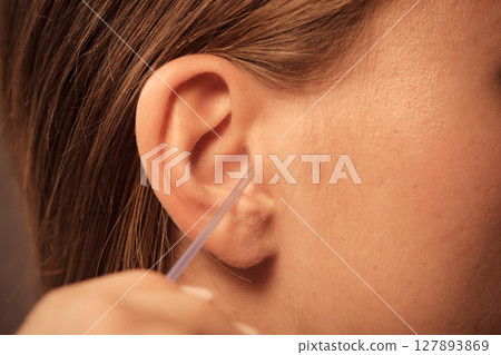Woman cleaning ear with cotton swabs closeup Woman cleaning ear with cotton swabs closeup 127893869
