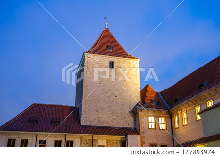 The Black Tower of Prague Castle stands majestically under the night sky, illuminated by warm street lamps. Its historical architecture offers a glimpse into Prague's rich heritage and beauty. 127893974