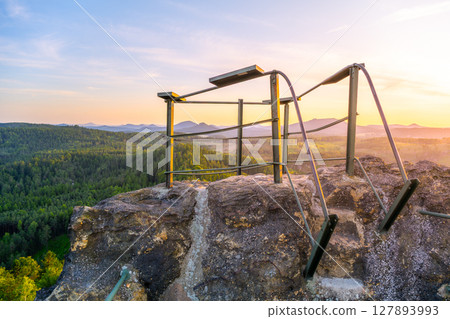 Enjoy a breathtaking sunset over the Lusatian Mountains from the rocky vantage point of Popov Cliffs. The warm evening light casts a golden hue across the sandstone formations and lush forests. Enjoy a breathtaking sunset over the Lusatian Mountains from the rocky vantage point of Popov Cliffs. The warm evening light casts a golden hue across the sandstone formations and lush forests. 127893993