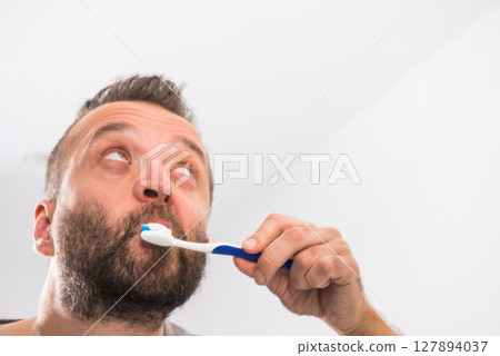 Man brushing his teeth in bathroom 127894037
