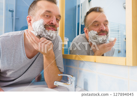 Guy shaving his beard in bathroom 127894045