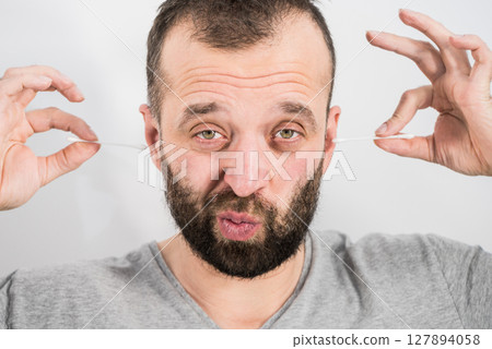 Man removing wax from ear using Q-tip 127894058