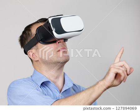 Man wearing virtual reality goggles on grey 127894069