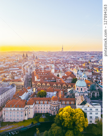 A breathtaking aerial perspective of Old Town Prague during sunrise showcases the vibrant rooftops and historic architecture. 127894163